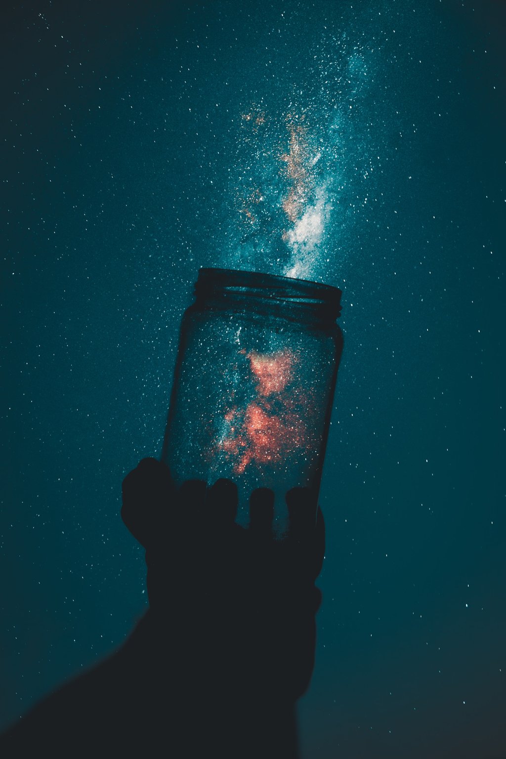 Person holding glass mason jar with night sky background