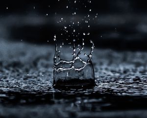 Rain drop bursting water particles upwards into the air